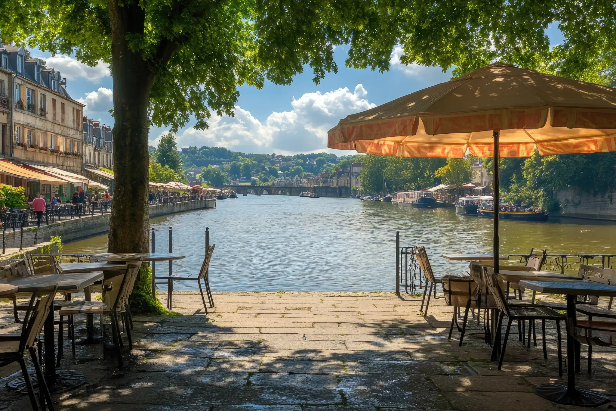 Terrasse de café ombragée au bord d’une rivière, sous un parasol